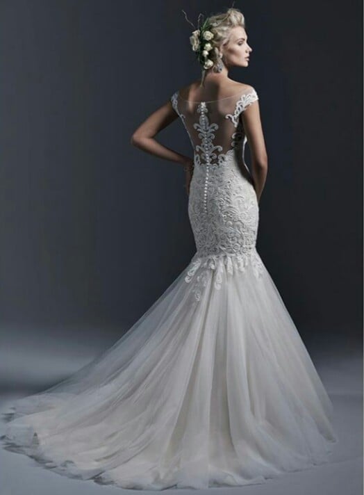 Woman in elegant white mermaid wedding dress with beaded bodice and cap sleeves