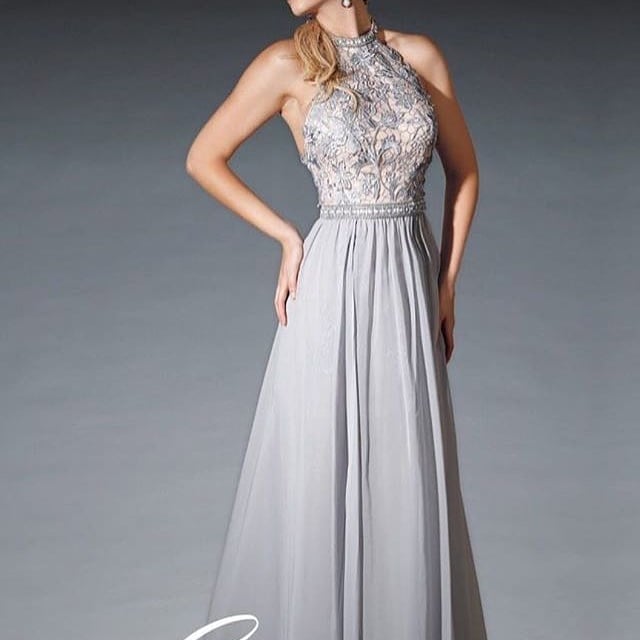 Woman wearing a silver sleeveless halter gown with beaded bodice and flowing chiffon skirt against gray background