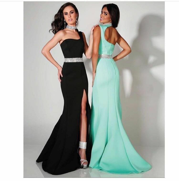 Two women modeling formal evening gowns in black and mint green