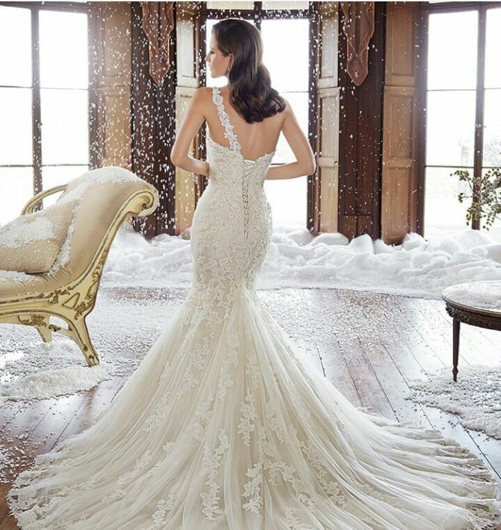 Bride in ornate beaded mermaid wedding dress with long train in snowy setting