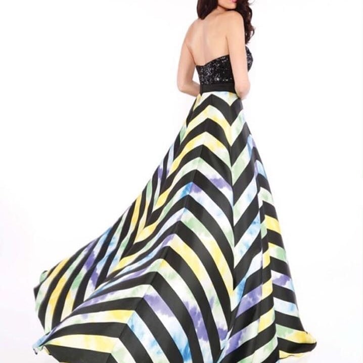 Woman in strapless black sequin top with colorful striped ball gown skirt