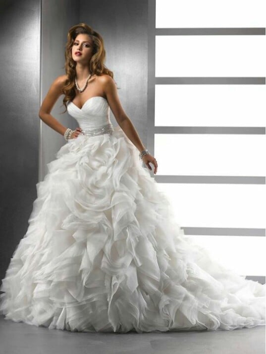 Woman in white strapless wedding dress with ruffled skirt and beaded waist