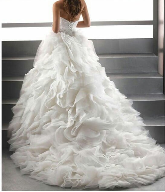 Bride in white ball gown wedding dress with ruffled skirt and long train